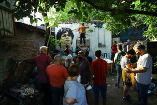 Поклонники Марадоны перед домом в пригороде Буэнос-Айреса Вилла Фьорито, где футболист провел детство