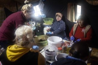 Добровольцы готовят еду в придорожном лагере на севере Киева