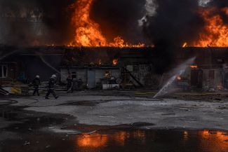 Пожарные тушат огонь на складе, воспламенившемся от попадания артиллерийского снаряда при обстреле российскими войсками Харькова. 28 марта 2022 года<br>