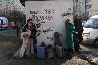 Украинская семья с вещами у попавшего под обстрел дома в Киеве