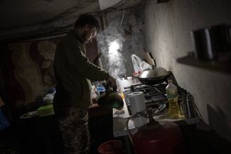 Украинский военный готовит еду в укрытии