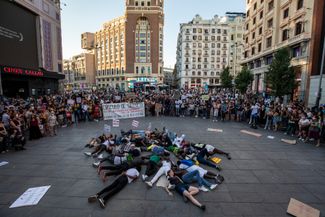 Протестующие лежат на площади, изображая погибших мигрантов на границе Испании и Марокко, во время демонстрации в Мадриде 1 июля 2022 года