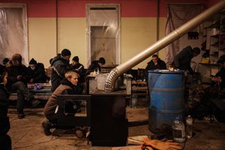 Украинка растапливает печь в центре гуманитарной помощи в Бахмуте