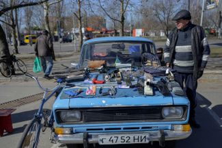 Мужчина продает подержанные вещи на капоте своей 47-летней машины. Николаев