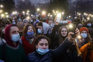 Протестующие зажигают фонарики на площади Ленина.