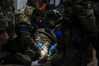 Украинскому военнослужащему оказывают первую помощь после боев в Соледаре