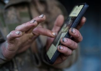 Private Andrei checks his mobile phone after returning from the front line