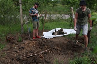 Волонтеры помогают эксгумировать останки российского военнослужащего, похороненного под крестом с табличкой «Неизвестный»