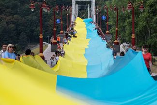 Активисты держат 430-метровый флаг Украины на пешеходном мосту через Днепр. Акция «Украина едина» символически объединяет оба берега Днепра и демонстрирует связь с регионами страны, которые находятся под российской оккупацией