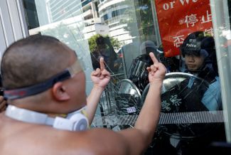 Протестующий пытается ворваться в здание законодательного совета Гонконга 1 июля 2018 года