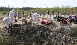Работники в защитных костюмах, занятые погребением скончавшихся от коронавируса на Новом Колпинском кладбище в Санкт-Петербурге. 25 мая 2020 года