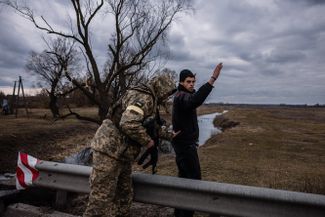 Украинский солдат обыскивает мужчину в деревне к востоку от города Бровары под Киевом