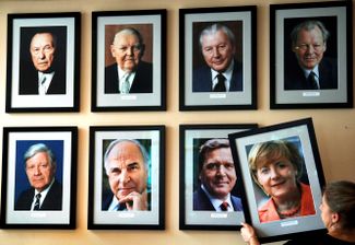 Портрет Ангелы Меркель, первой женщины — канцлера ФРГ, вешают возле фотографий предыдущих глав правительства страны в берлинской гостинице KanzlerEck («Уголок канцлера»). 23 ноября 2005 года