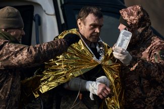 Украинские военные помогают раненому товарищу