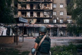 Украинский военный на фоне разрушенного жилого дома в Северске. До войны в городе жили около 10 тысяч человек, но он был практически полностью разрушен в ходе боев, которые продолжаются больше месяца. В ДНР еще в середине июля <a href="https://www.interfax.ru/world/852126" rel="noopener noreferrer" target="_blank">объявили</a> о том, что город был полностью окружен. Однако украинские волонтеры, раздававшие гуманитарную помощь, добирались туда вплоть до 8 августа