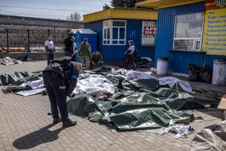 Ukrainian police officers next to the bodies of missile strike victims