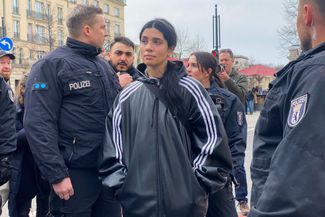 Nadezhda Tolokonnikova surrounded by police officers. Police asked protesters to remove their balaclavas.