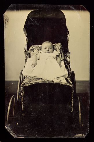 Портрет новорожденного в коляске в студии