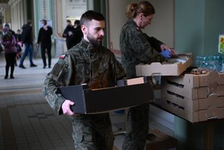Polish soldiers carry boxes of food for refugees at a train station in Przemyśl in southern Poland. February 25, 2022.