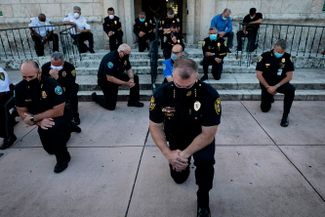 Полицейские преклонили колени в знак солидарности с участниками митинга в городе Корал-Гейблс (штата Флорида), 30 мая 2020 года