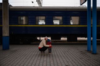 Женщина утешает своего сына после прибытия в эвакуацию в Запорожье. 17 апреля 2022 года