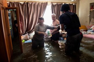Жители Херсона пытаются спасти хоть какие-то вещи из своей затопленной квартиры перед эвакуацией