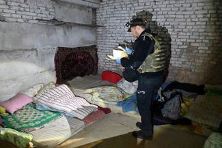 Полицейский осматривает подвал детского сада, который использовался войсками РФ как база в селе Липцы