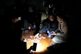 Жители Львова играют в карты в бомбоубежище, освещая игровой стол фонариками смартфонов