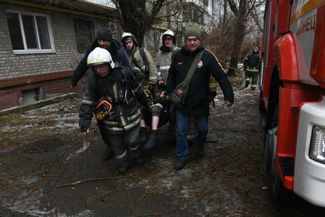 Сотрудники МЧС несут жительницу Донецка, раненную во время украинского обстрела