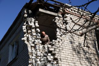 Украинский военный Александр выглядывает из пробитой стены одного из жилых домов Великой Новоселки