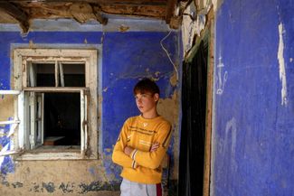 Мальчик возле разрушенного российской авиацией дома в поселке Маяки