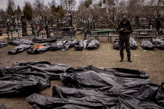 Мужчина переписывает людей, убитых в Буче. Всего в марте в Буче захоронили 340 человек, сообщила ритуальная служба города. Людей хоронят в братских могилах и во дворах жилых домов