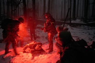 Украинские военные готовятся эвакуировать раненого сослуживца, наступившего на «лепестковую» мину в лесу под Купянском. Такие мины устанавливаются с помощью средств дистанционного минирования, в том числе при помощи артиллерии или систем залпового огня