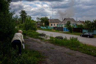 Женщина пытается укрыться от артиллерийского обстрела в селе под Харьковом