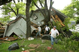 Друзья помогают хозяину разрушенного дома вынести уцелевшие вещи в городе Уимберли, штат Техас. 24 мая 2015 года