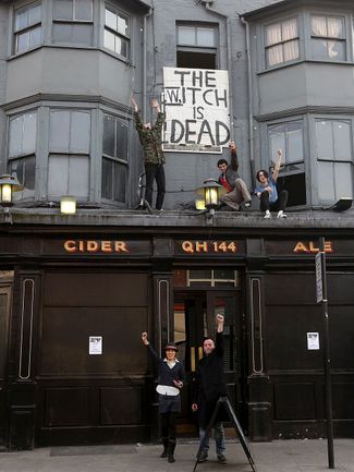 Люди в Брикстоне, Лондон, приветствуют смерть Маргарет Тэтчер плакатом «Ведьма мертва». 8 апреля 2013 года
