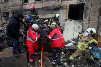 Медики и пожарные эвакуируют пострадавшего в результате удара в центре Киева.