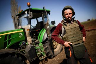 Украинский фермер в бронежилете и каске работает в поле