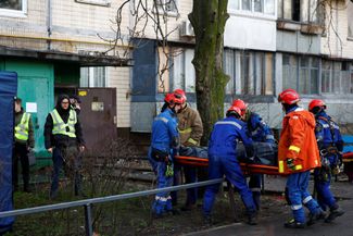Rescue workers carry the body of a victim found under the debris of an apartment building hit in Russia’s attack on Kyiv. November 14, 2025.