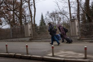Civilians in Kyiv, carrying their belongings, run to the train station as air-raid sirens sound. 