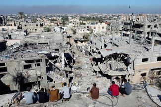 Палестинцы смотрят на дома, разрушенные в результате израильских ударов. Лагерь беженцев Хан-Юнис на юге сектора Газа, 29 ноября 2023 года