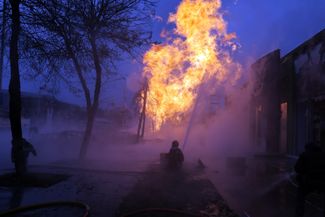 Пожарный борется с возгоранием, возникшим в результате падения обломков ракеты в Подольском районе Киева.