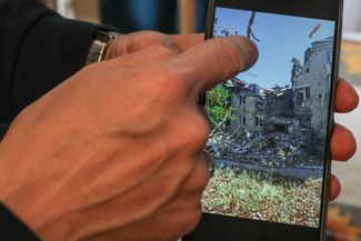 Виталий показывает фото своего разрушенного дома в Алешках
