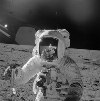 Астронавт NASA и пилот лунного модуля Apollo 12 Алан Бин держит в руках герметичный контейнер для сбора лунного грунта, в то время как командир корабля Пит Конрад фотографирует его на черно-белую пленку ручной камерой Hasselblad. Фотокамеры для лунных выходов использовались практически серийные, но модернизированные NASA. В частности, из них удалялась вся смазка, чтобы ее испарение не загрязнило пленку; на линии зрения в камеру добавлялось стекло с антистатическим покрытием и крестовыми насечками для облегчения работы <a href="https://ru.wikipedia.org/wiki/%D0%A4%D0%BE%D1%82%D0%BE%D0%B3%D1%80%D0%B0%D0%BC%D0%BC%D0%B5%D1%82%D1%80%D0%B8%D1%8F" rel="noopener noreferrer" target="_blank">фотограмметристам</a> NASA; камеры для выхода на поверхность покрывались светоотражающей краской для избежания перегрева от солнечного света, а кассеты использовались увеличенного размера — на 160 цветных кадров или 200 черно-белых, — для чего компания Kodak специально разработала более тонкую пленку.