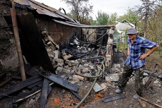 75-летний местный житель Владислав Дрига рядом с разрушенной в результате обстрела пристройкой своего дома
