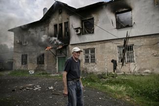 Мужчина стоит перед своим горящим домом в Лисичанске. Украинские войска продолжают держать оборону Луганской области