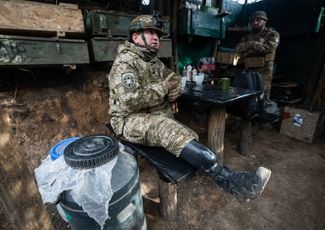 32-летний украинский солдат Артем, потерявший ногу в бою и вернувшийся на фронт после протезирования, обедает с сослуживцами на позициях ВСУ под Бахмутом