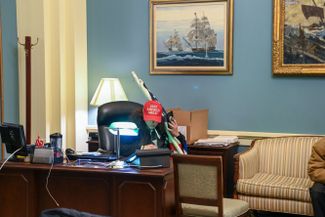 Сторонник Трампа в кепке его избирательной кампании в одном из захваченных кабинетов Капитолия. Вашингтон, 6 января 2021 года<br><br>
