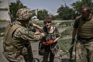Украинские военнослужащие оказывают помощь раненной во время обстрела женщине, Лисичанск