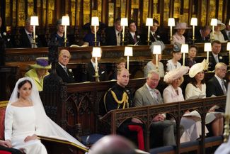 Меган Маркл в часовне святого Георгия. В среднем ряду слева направо: королева Елизавета II, герцог Эдинбургский, граф Уэссекский, виконт Севернский, графиня Уэссекская и другие. В нижнем ряду слева направо: принц Уильям (брат жениха), принц Уэльский Чарльз, его жена герцогиня Корнуольская Камилла Паркер-Боулз, жена принца Уильяма герцогиня Кембриджская Кэтрин Миддлтон, герцог Йоркский
